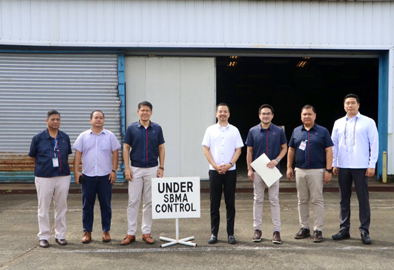SBMA Chairman and Administrator Jonathan D Tan and agency officials pose beside an ultralight aircraft manufactured by Ramphos Corporation during the agency&#39;s takeover of company properties at the Subic Bay International Airport on Tuesday. Contractual defaults and the expiration of the lease agreement prompted the agency to take over the company&#39;s properties.