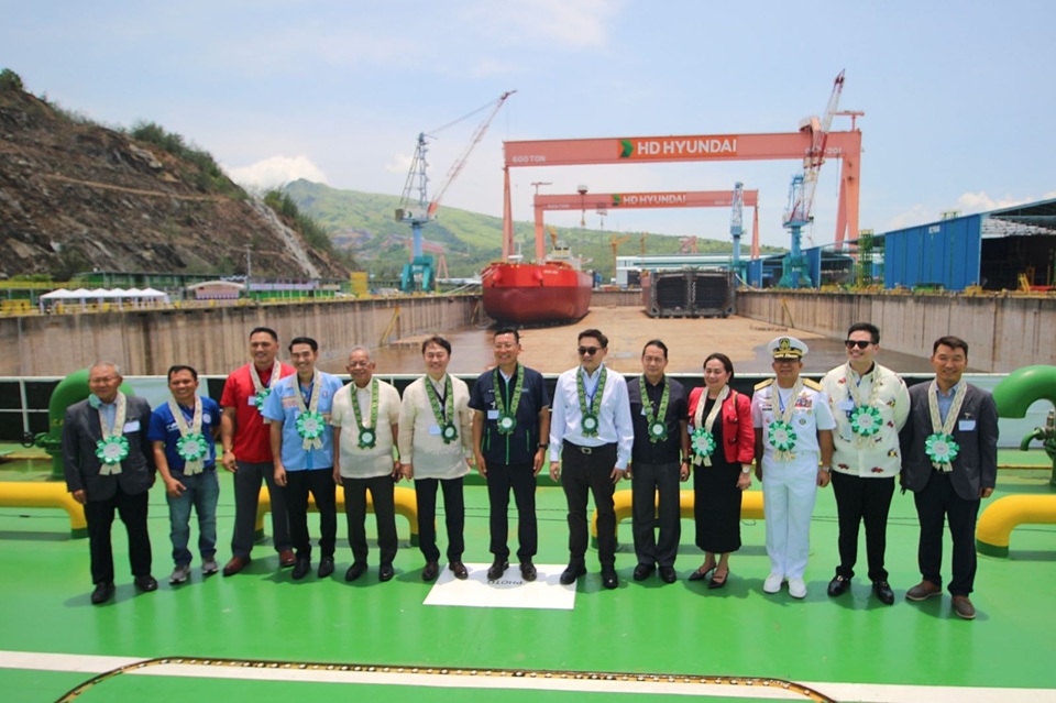 Guests of honor pose for a souvenir photo with the first Filipino-built vessel, Orion Jade, behind them, at the HD Hyundai Heavy Industries Philippines (HHIP) Inc. on July 28, 2026.